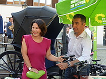 Zwei glückliche Spitzenkandidaten unter dem Sonnenschirm der Grünen Partei, man sieht ein Lastenfahrrad als E-Bike und eine alte Kutsche. Es handelt sich um den Bürgerdialog, dem AUftakt der Wahlkampftour in Potsdam mit Cem Özdemir, dem Spitzenkandidaten für die Bundestagswahl 2017. Annalena trägt ein pinkes Kleid, Cem ein helles Hemd, beide wirken sorglos und fröhlich.