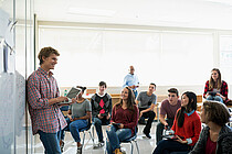 Ein Jugendlicher steht an einer Tafel, andere Teenager sitzen auf Stühlen in einem US-amerikanischen Klassenraum