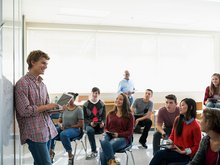 Ein Jugendlicher steht an einer Tafel, andere Teenager sitzen auf Stühlen in einem US-amerikanischen Klassenraum