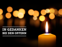 Brennende Kerzen, verwischt, eine leuchtend im Vordergrund. Dazu die Aufschrift: In Gedanken bei den Opfern.