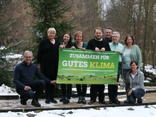 Der Landesvorstand - neun Frauen und Männer - halten das Poster hoch: "Zusammen für gutes Klima" - sie posieren im Winter neben dem Gebäude des Waldsolarheims in Eberswalde.